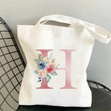 a white tote bag with a floral initial