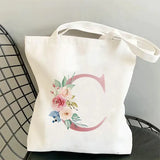 a white tote bag with a pink flower on it