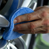 someone wiping a car wheel with a micro towel