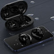 Wireless earbuds with their charging case and a smartphone.