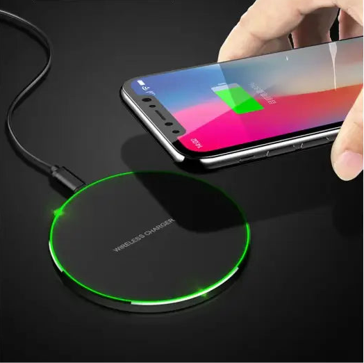 Wireless charging pad with a glowing green edge illuminating a smartphone being placed on it.