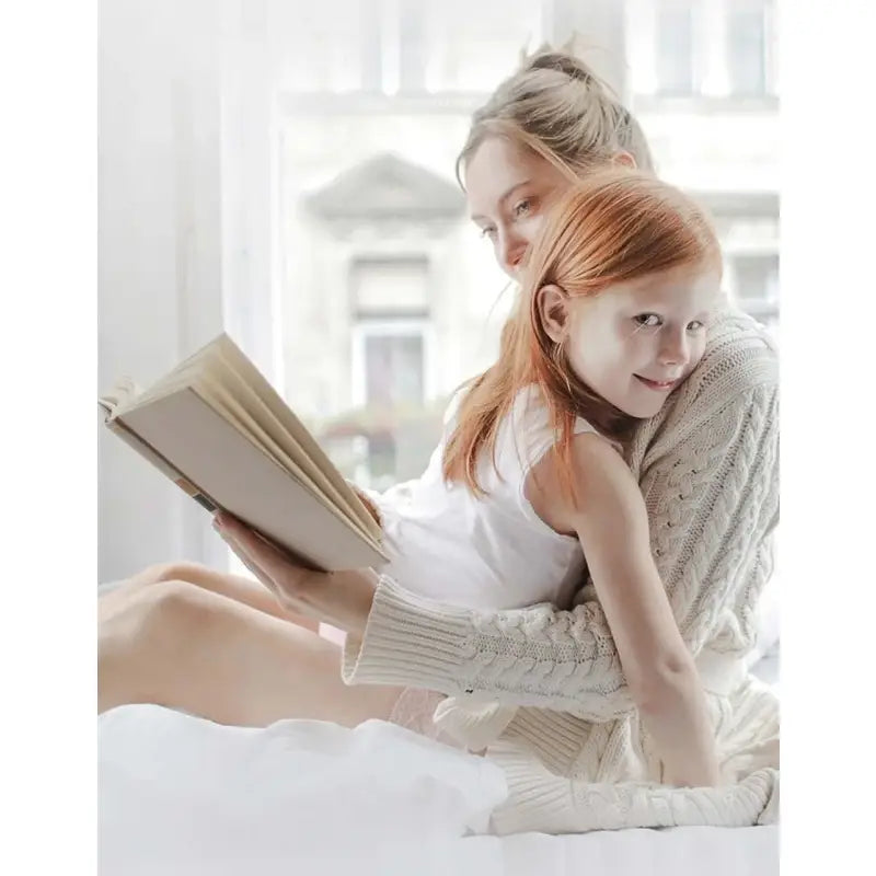 a woman sitting on a bed reading a book