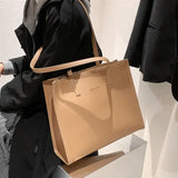 a woman holding a beige bag in her hand