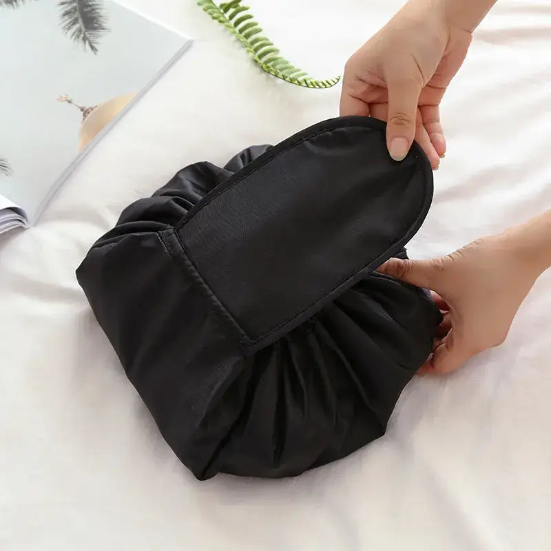 a woman is holding a black bag on a bed