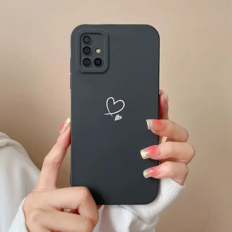 a woman holding a black iphone case with a heart sticker on it