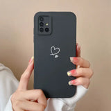 a woman holding a black iphone case with a heart sticker on it