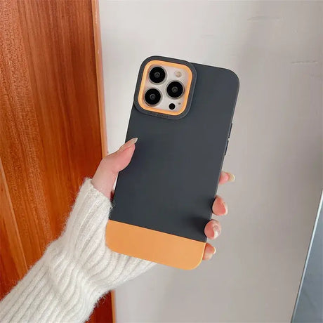 A woman holding a black and orange iphone case