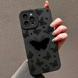 a woman holding a black phone case with a black butterfly design