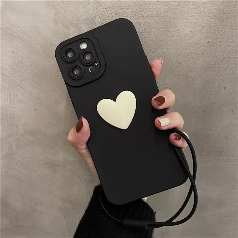 a woman holding a black phone case with a heart