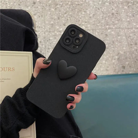 A woman holding a black phone case with a heart shaped design