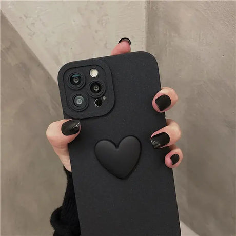 A woman holding a black phone case with a heart on it