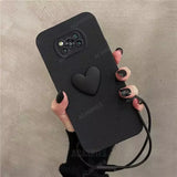 A woman holding a black phone case with a heart on it