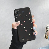 a woman holding up a black phone case with hearts on it