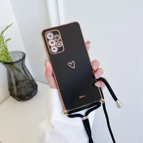 A woman holding a black phone case with a heart on it