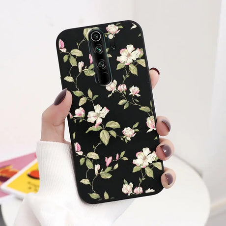 A woman holding a black phone case with pink flowers on it