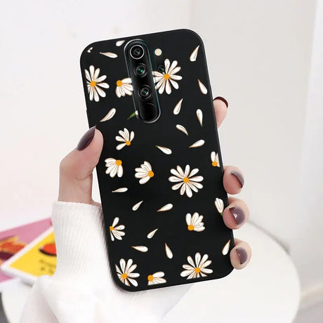 A woman holding a black phone case with white daisies on it