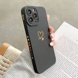 A woman holding a black phone case with gold heart