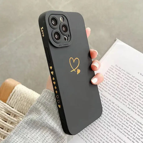 A woman holding a black phone case with gold heart
