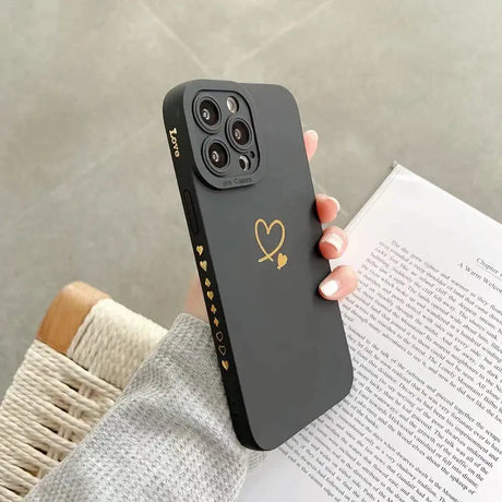 A woman holding a black phone case with a heart on it