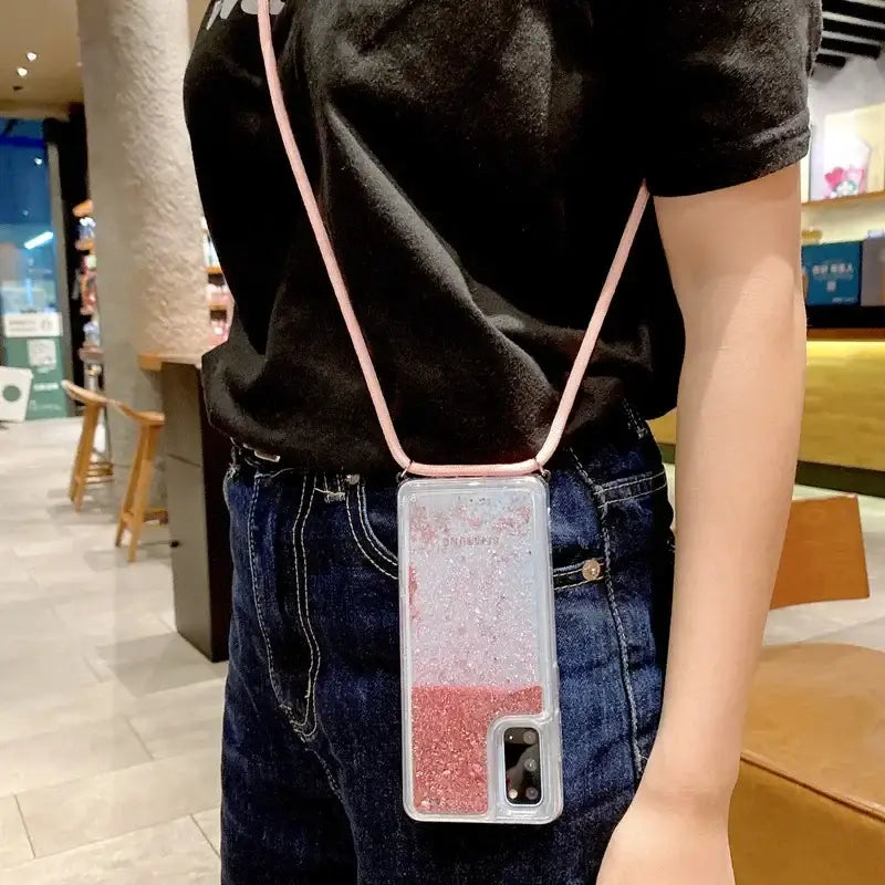 a woman wearing a black shirt and jeans holding a pink phone case