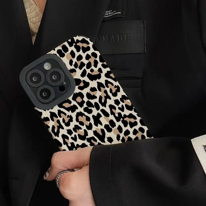 a woman in a black suit holding a leopard print phone case