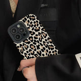 a woman in a black suit holding a leopard print phone case