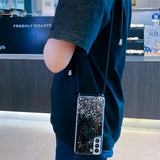 a woman holding a black and white glitter phone case