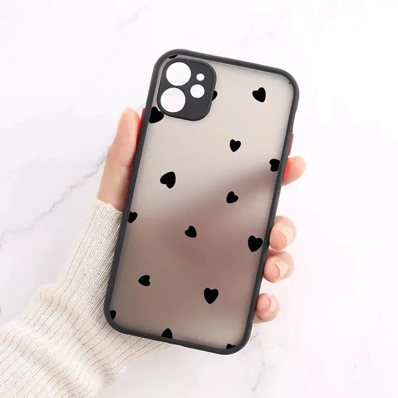 a woman holding a black and white heart iphone case