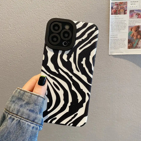 A woman holding up a black and white zebra print phone case