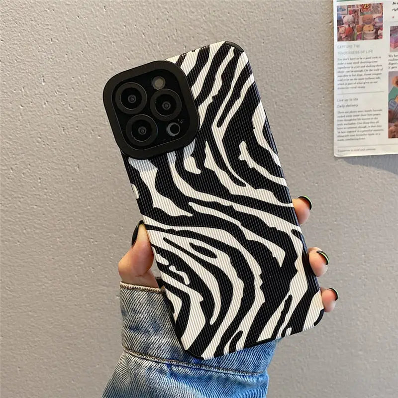 a woman holding a black and white zebra print phone case