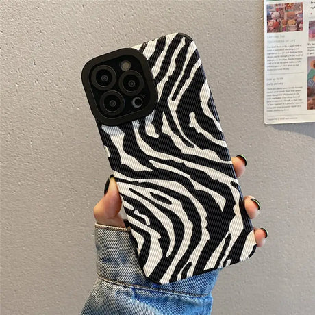 A woman holding a black and white zebra print phone case