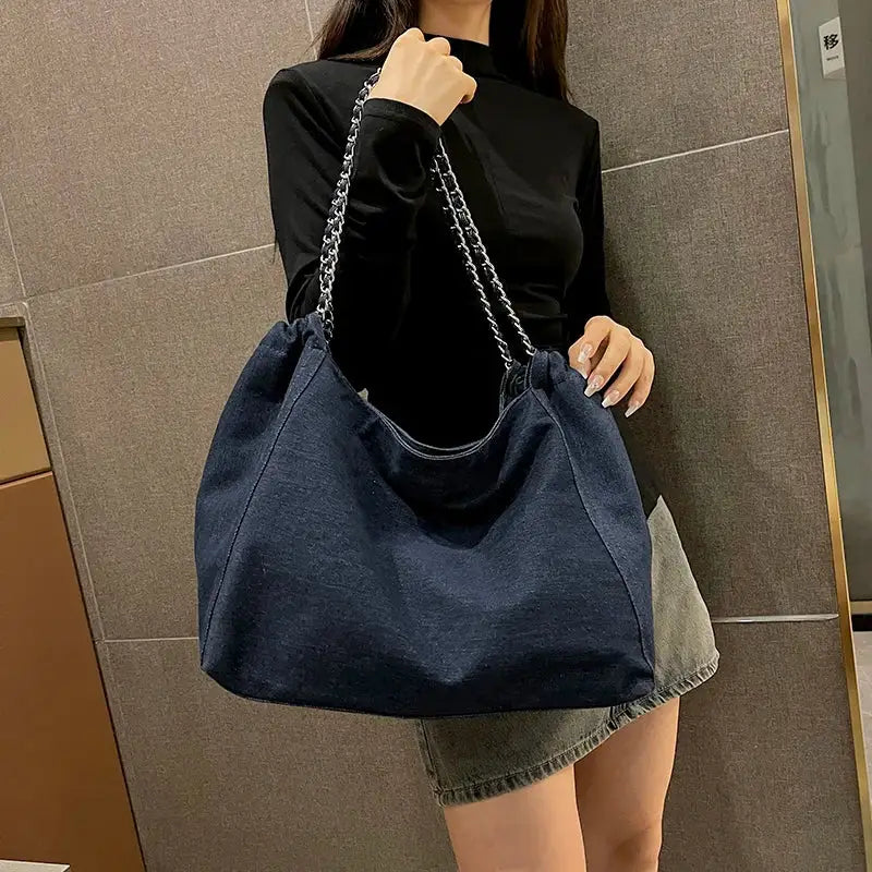 a woman holding a blue denim bag