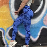 a woman in blue leggings and white sneakers stands against a graffiti wall