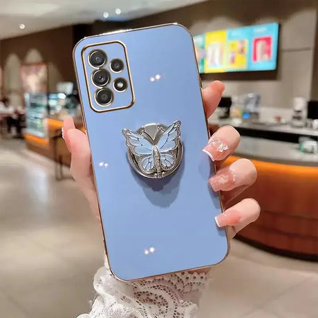 A woman holding a blue phone case with a butterfly on it