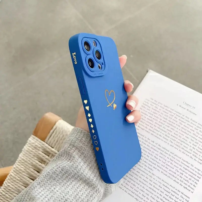 a woman holding a blue phone case with a heart on it