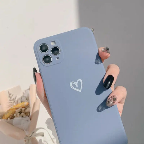 A woman holding a blue phone case with a heart on it