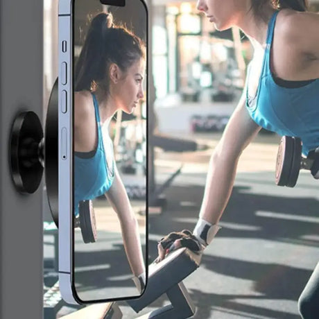 a woman in a blue tank top is holding a cell phone