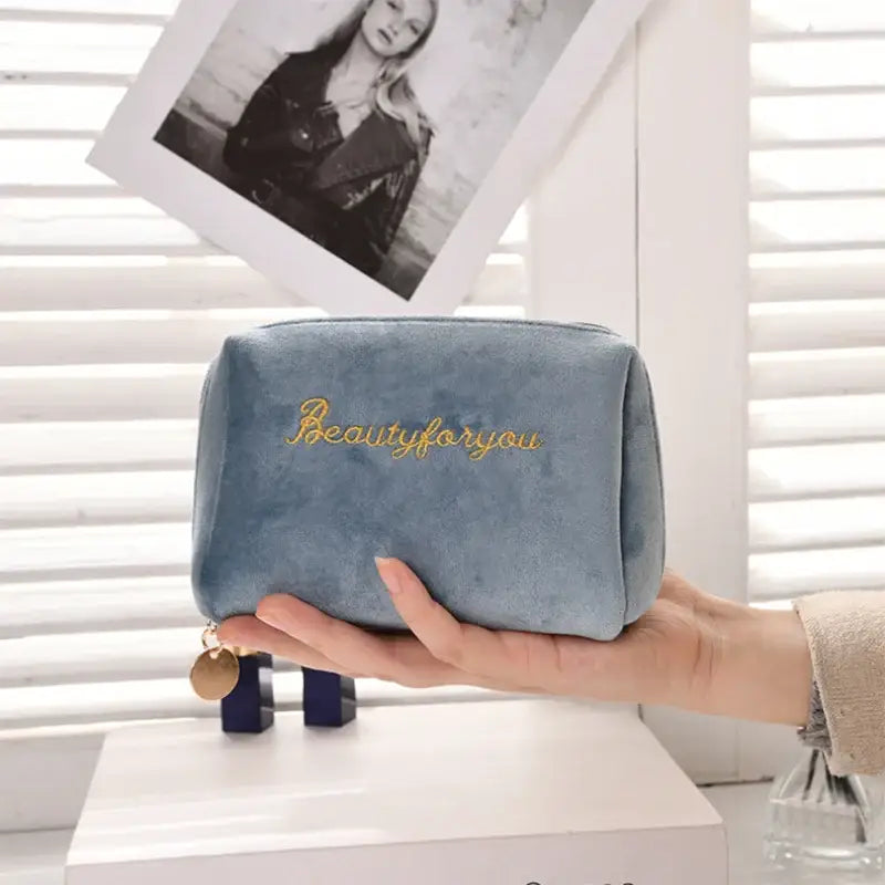 a woman holding a blue velvet bag with the word beautiful