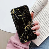 A woman holding a book and a black marble phone case