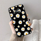 a woman holding a book and a phone case with daisies on it