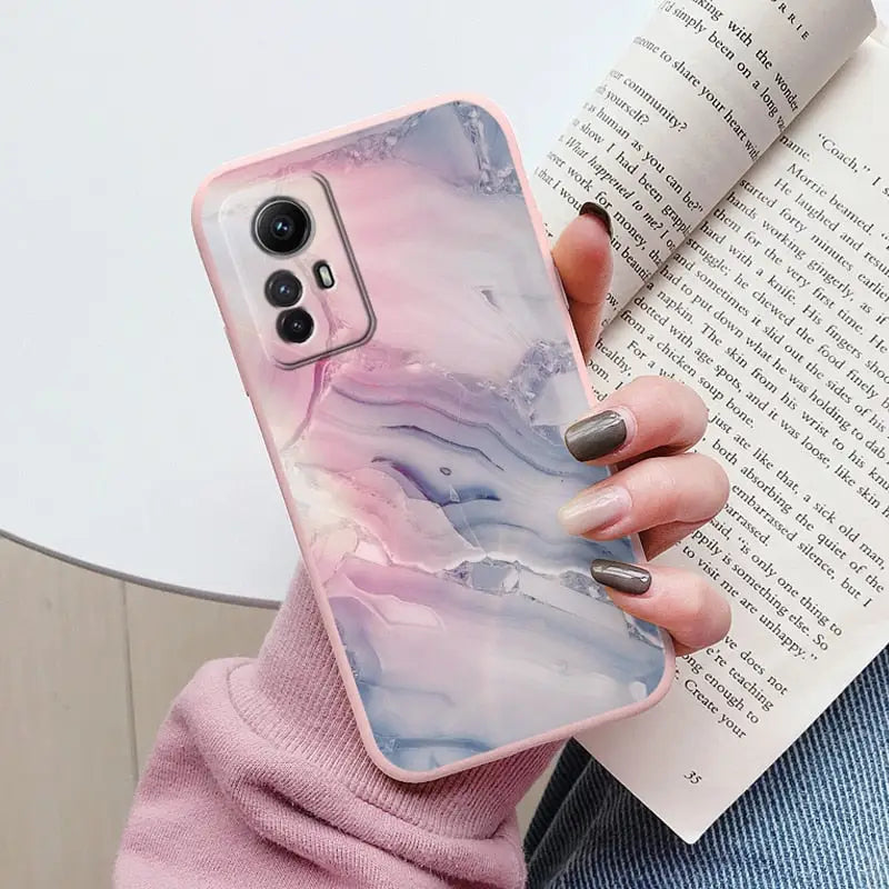 a woman holding a book and holding a phone case