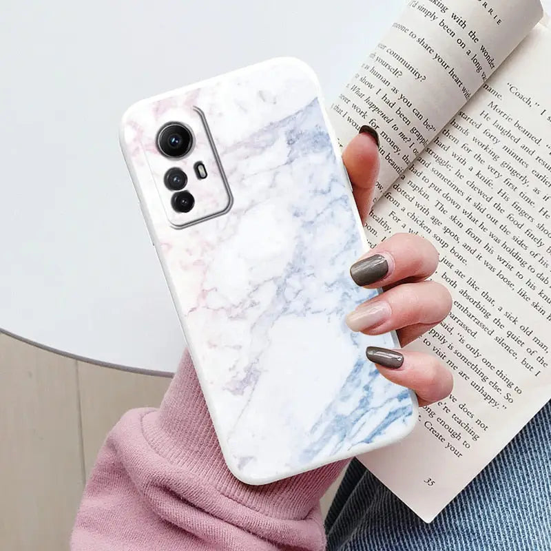 a woman holding a book and a phone case with a marble design