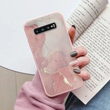 a woman holding a book and a pink marble phone case