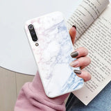 a woman holding a book and a white marble phone case