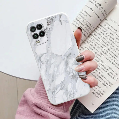 a woman holding a book and a white marble phone case