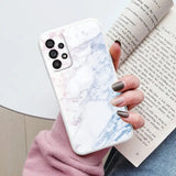 a woman holding a book and a white marble phone case