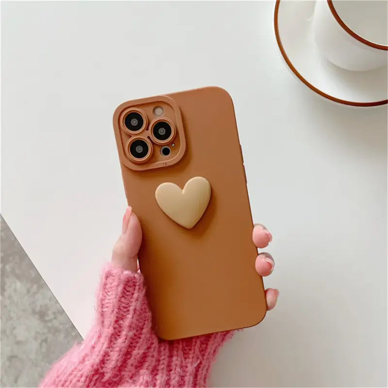 a woman holding a brown iphone case with a heart