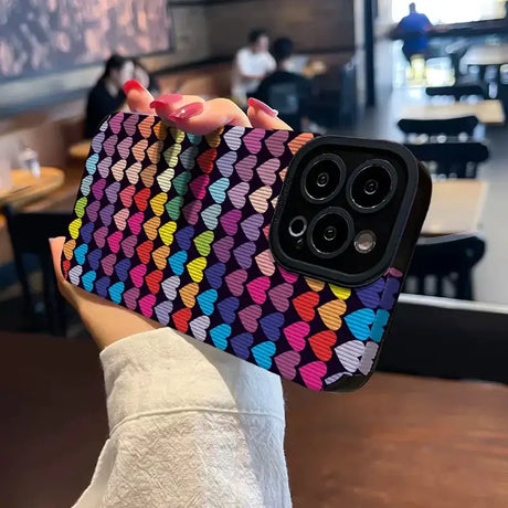 A woman holding up a colorful heart pattern case