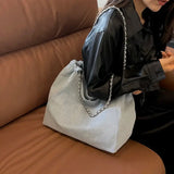 a woman sitting on a couch holding a gray bag