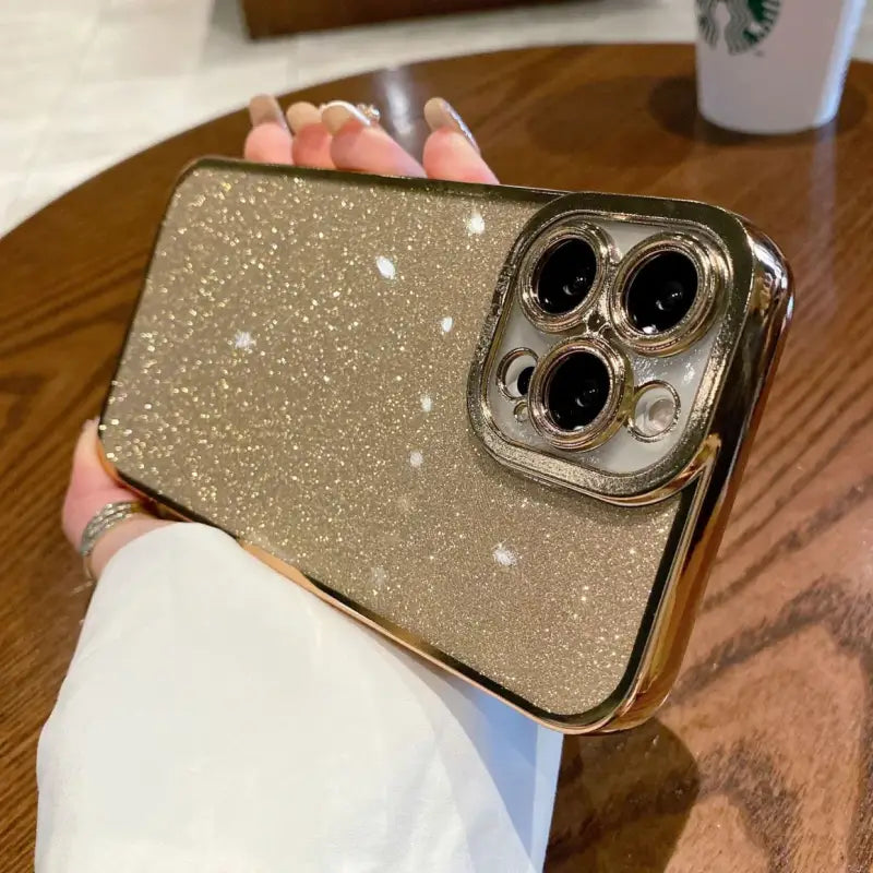 a woman holding a gold glitter phone case